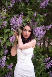 Portrait of beautiful woman standing against purple flowering plants