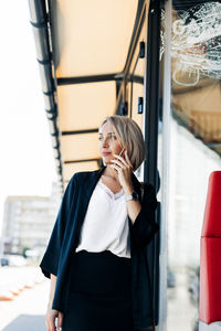 Portrait of young business woman talking on the phone while standing outdoors at the street