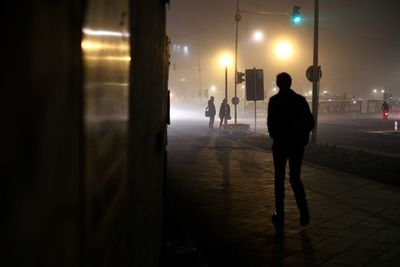 Rear view of man walking in illuminated corridor