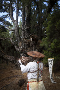 Rear view of woman standing in forest