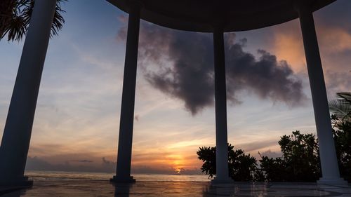 Silhouette palm trees by sea against sky during sunset