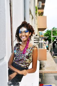 Portrait of smiling young woman standing against building