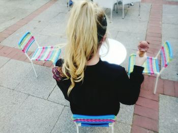 Rear view of woman holding ice cream cone at restaurant