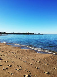 Scenic view of beach against clear blue sky