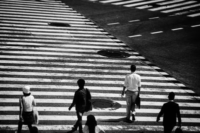 Rear view of people walking on zebra crossing 