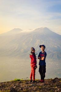 Full length of friends standing on mountain against sky