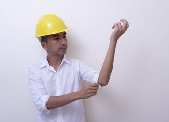 Young man looking away while standing against white background