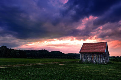 Barn on field against sky during sunset