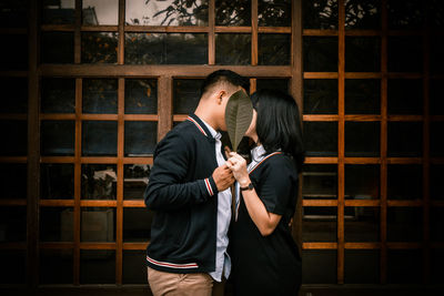 Rear view of couple standing against the wall