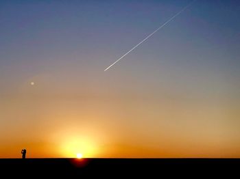 Low angle view of vapor trails in sky during sunset