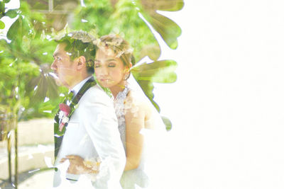 Midsection of couple holding hands while standing against white background