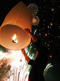 Low angle view of man releasing lantern in the dark