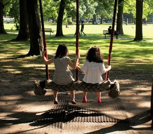 Children sitting on swing in park