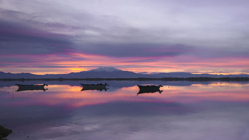 Scenic view of lake against dramatic sky during sunset