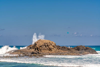 Rocks on beach against blue sky