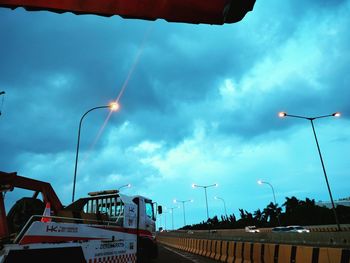 Low angle view of illuminated street light by building against sky