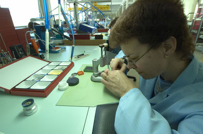 Female watch maker working in industry