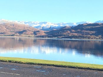 Scenic view of lake by mountains against clear sky