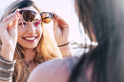 Smiling woman showing sunglasses to friend