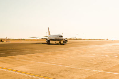 Airplane on airport runway against clear sky