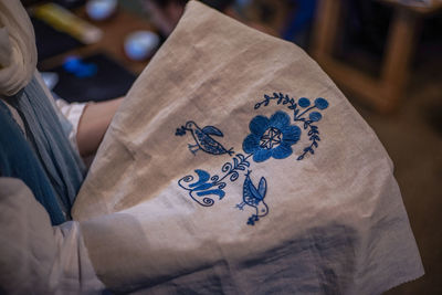 Midsection of person holding embroidered textile