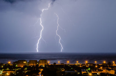 Panoramic view of lightning over sea against sky at night