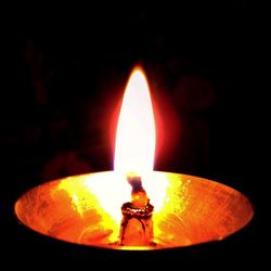 Close-up of lit candle against black background