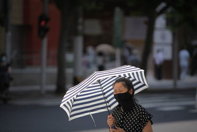 Woman with umbrella standing on street in rain