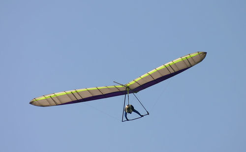 Low angle view of man paragliding against clear blue sky