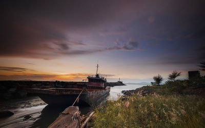 Sailboat moored on sea against sky during sunset