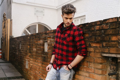 Handsome man standing against brick wall