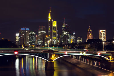 Illuminated bridge over river main in city at night