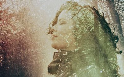 Young woman with bare tree in water