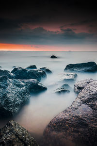 Scenic view of rocks in sea during sunset