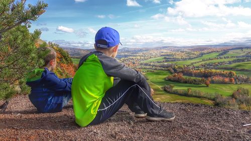 Siblings sitting on field against landscape