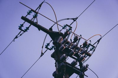 Low angle view of electricity pylon against clear blue sky