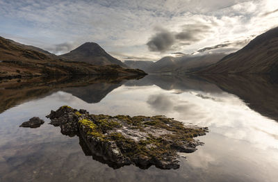 Scenic view of lake and mountains against cloudy sky