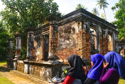 Woman with friends riding motor scooter by old ruins