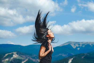 Woman with arms raised against sky