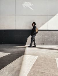 Side view of young man walking on concrete wall