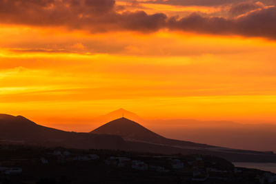 Scenic view of silhouette mountains against romantic sky at sunset