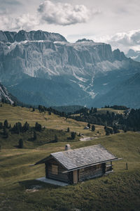 House on field by mountain against sky