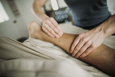 Massage therapist uses her hands to work on calf of patient