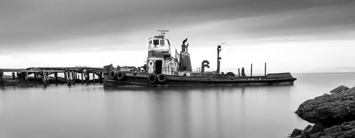 Ship moored at harbor against sky