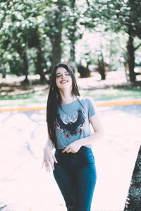 Beautiful young woman standing against trees