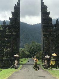 People on walkway amidst buildings against mountains