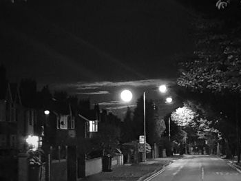 Empty road along illuminated street lights at night