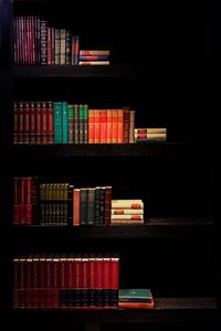 Low angle view of books on shelf against black background