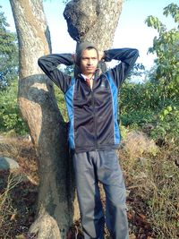 Portrait of teenage boy standing on tree trunk