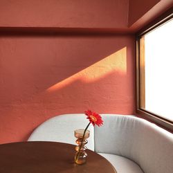 Close-up of red flower vase on table against wall